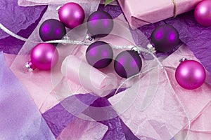 Merry Christmas and Happy New Year greeting card. Gift boxes with pink and purple decorations on the crumpled paper background.
