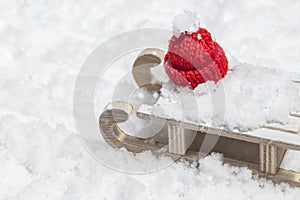 Merry Christmas and Happy New Year greeting card with wooden sleigh and red christmas cap on snow