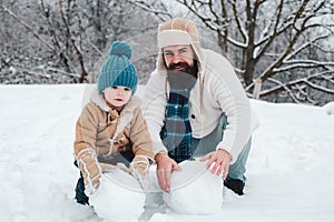 Merry Christmas and Happy New Year. Happy father and son making snowman in the snow. Handmade funny snow man. Winter