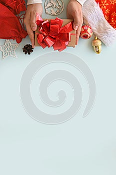 Merry Christmas and Happy New Year. A man`s hands hold a gift box in kraft paper next to other surprises in bags