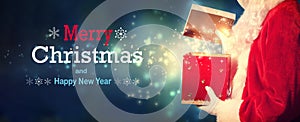 Merry Christmas and Happy New year message with Santa opening a gift box