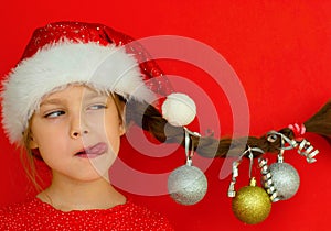 Merry Christmas and happy New year. Portrait of a beautiful smiling girl in a red dress and Santa hat, with a pigtail on