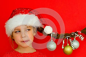 Merry Christmas and happy New year. Portrait of a beautiful smiling girl in a red dress and Santa hat, with a pigtail on