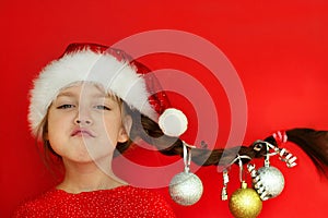 Merry Christmas and happy New year. Portrait of a beautiful smiling girl in a red dress and Santa hat, with a pigtail on