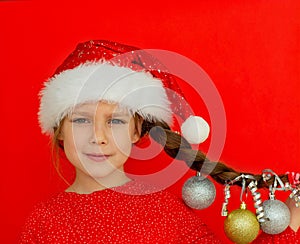 Merry Christmas and happy New year. Portrait of a beautiful smiling girl in a red dress and Santa hat, with a pigtail on