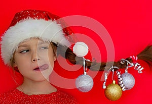 Merry Christmas and happy New year. Portrait of a beautiful smiling girl in a red dress and Santa hat, with a pigtail on