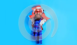 Merry Christmas and Happy New Year. Smiling bearded man in Santa hat looking through paper hole. Santa man in party