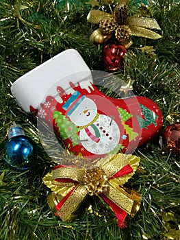 Merry Christmas and Happy New Year, snowman sock Tin Box, ribbon and ornaments decoration with green tinsel background