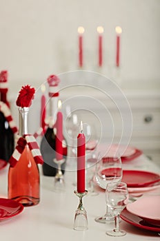 Merry Christmas and Happy New Year! Table setting - red and pink dishes, holiday knitted decor - Santa Claus knitted hats on the