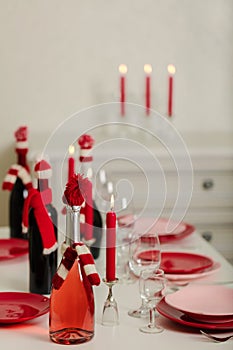 Merry Christmas and Happy New Year! Table setting - red and pink dishes, holiday knitted decor - Santa Claus knitted hats on the
