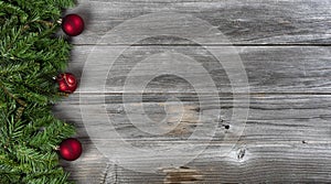 Merry Christmas and Happy New Year theme consisting of fir branches and red ball ornaments on left side of rustic wooden boards