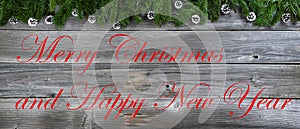 Merry Christmas and Happy New Year theme with fir branches plus pinecone ornaments on rustic wood