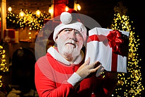 Merry Christmas and Happy New Year. Thoughtful Santa Claus with Christmas gift. Pensive bearded man in Santa Claus