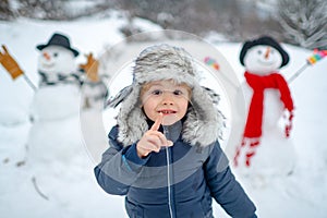 Merry Christmas and Happy new year. Winter portrait of little boy child in snow Garden make snowman. Cute kid - winter
