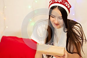 Merry Christmas and happy new year. Young woman in bed in pajamas opens gifts for winter holidays