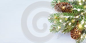 Merry Christmas holiday card or banner with snowy fir branches and conifer cones. Magic bokeh lights