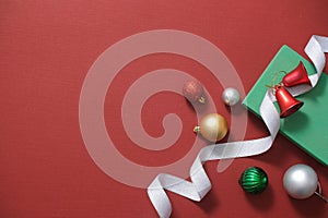 Merry Christmas holiday concept. Christmas decorations baubles, bells, ribbons and gift box on red background.