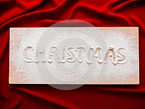 Merry Christmas Inscription on a wooden board Christmas Background, Top View. Concept baner card on red cloth
