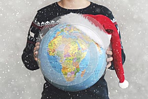 Merry Christmas. kid holding earth globe with a Santa hat