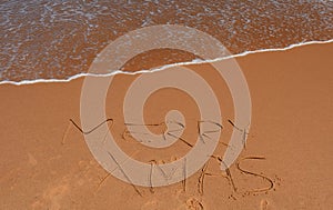 Merry Christmas lettering on the beach.