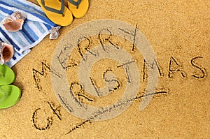 Merry Christmas message written in sand on a sunny tropical beach, Christmas holiday vacation concept