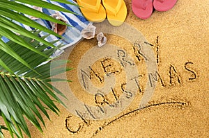 Merry Christmas message written in sand on a sunny tropical beach, Christmas holiday vacation concept