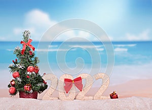 Merry Christmas. New Year concept. Christmas tree on a hot beach and the inscription 2022 on sand