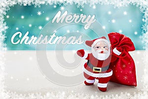 Merry Christmas over blurred blue background with Santa Claus and red gift bag