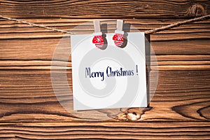 Merry christmas phrase on little kraft paper stickers hanging on a rope on wooden clothespins. Santa Claus.  Rustic Christmas