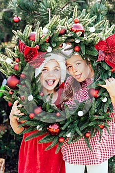 Merry Christmas. Portrait of two happy funny children girls in Santa hat with Christmas wreath