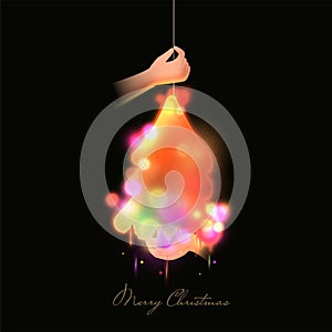 Merry Christmas Poster Design With Hand Holding Ceiling Lamp And Bokeh Effect On Black