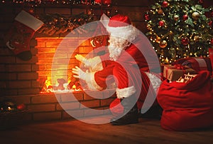 Merry Christmas! santa claus near the fireplace and tree with gi