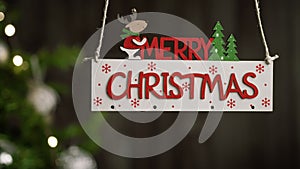 Merry Christmas sign hanging with tree on the background