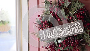 Merry Christmas sign and wreath on door on sunny Christmas morning