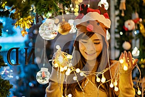 Merry Christmas, Smiling beautiful young asian woman with a glowing Christmas garland