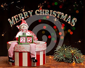 Merry Christmas! A snowman figure on a decoupage box holds two cubes forming the number twenty-five