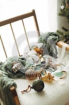 Merry Christmas! Stylish christmas vintage baubles, ribbons, brass bells and scissors on cozy white chair. Christmas ornaments