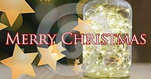 Merry christmas text banner and yellow star icons against fairy lights in a glass jar