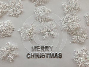 Merry christmas text on white background covered with snowflakes. Christmas concept. Silver letters. copy space