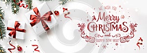 Merry Christmas text on white background with gift boxes, fir branches, red decoration. Xmas and New Year greeting card, bokeh,