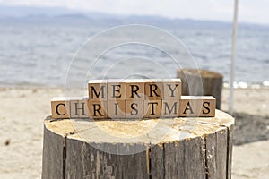 Merry christmas text from wooden cubes. The cubes are on the tree stump