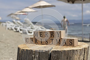 Merry christmas text from wooden cubes. The cubes are on the tree stump