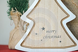 `Merry Christmas` text on wooden tree decoration. Happy Holidays background image