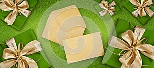 Merry christmas, top view of wrapped gift present packages with golden ribbon bow, envelope and greeting card , isolated on green