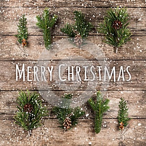 Merry Christmas Typographical on wooden background with fir branches, pine cones and snowflakes on wooden background. Xmas and New