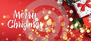 Merry christmas wish banner on red background with new year gifts and decorations, top view with bokeh