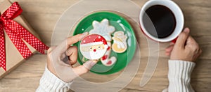 Merry Christmas with woman hand holding coffee cup and homemade cookie on table. Xmas eve, party, holiday and happy New Year