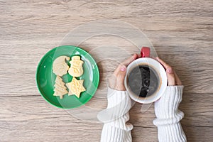 Merry Christmas with woman hand holding coffee cup and homemade cookie on table. Xmas eve, party, holiday and happy New Year