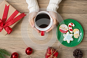 Merry Christmas with woman hand holding coffee cup and homemade cookie on table. Xmas eve, party, holiday and happy New Year