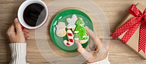 Merry Christmas with woman hand holding coffee cup and homemade cookie on table. Xmas eve, party, holiday and happy New Year